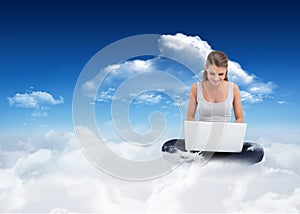 Composite image of cross-legged woman using a laptop