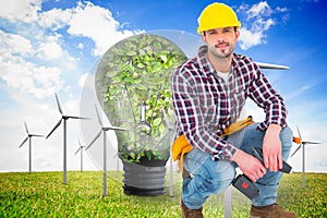 Composite image of crouching handyman holding power drill