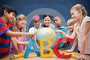 Composite image of cute pupils and teacher looking at globe in library