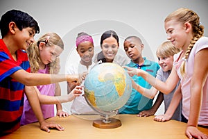 Composite image of cute pupils and teacher looking at globe in library