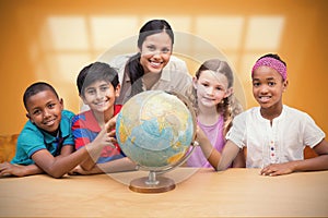 Composite image of cute pupils and teacher looking at globe in library