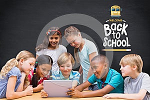 Composite image of cute pupils using tablet computer in library