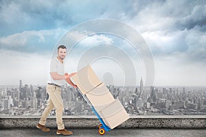 Composite image of delivery man pushing trolley of boxes