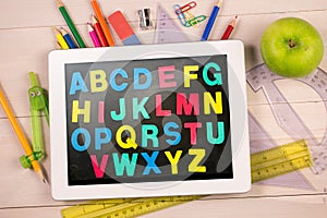 Composite image of digital tablet on students desk