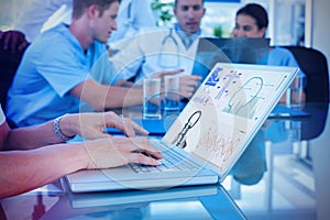 Composite image of doctor typing on keyboard with her team behind