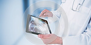 Composite image of doctor using digital tablet