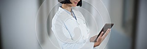 Composite image of doctor using digital tablet against white background