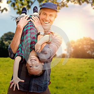 Composite image of father holding his son upside down photo