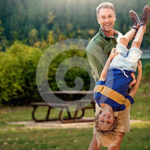 Composite image of father holding son upside-down photo