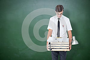 Composite image of fired businessman holding box of belongings