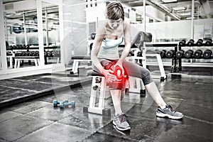 Composite image of fit brunette sitting on bench holding injured knee