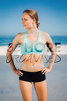 A Composite image of fit woman standing on the beach with hands on hips