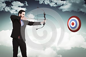 Composite image of focused businessman shooting a bow and arrow