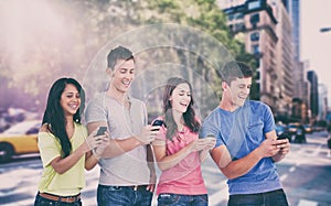 Composite image of four laughing friends sending texts on their phones