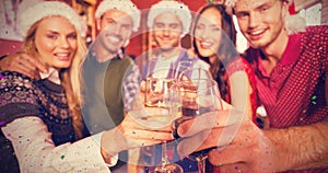 Composite image of friends wearing christmas hats while toasting
