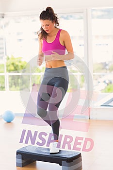 A Composite image of full length of a fit woman performing step aerobics exercise