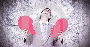 Composite image of geeky businessman crying and holding broken heart card