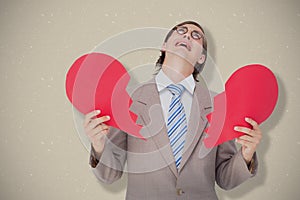 Composite image of geeky businessman crying and holding broken heart card