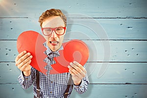 Composite image of geeky hipster holding a broken heart