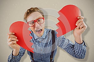 Composite image of geeky hipster holding a broken heart