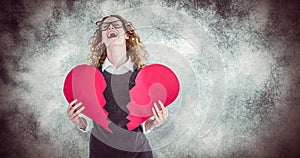 Composite image of geeky hipster holding a broken heart card