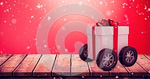 Composite image of gift box with red ribbon on wheels