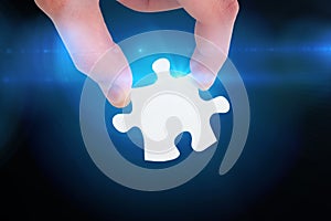 Composite image of hand holding jigsaw piece