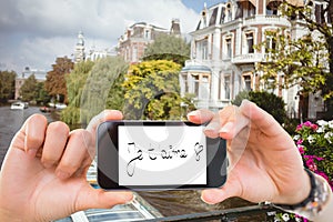 Composite image of hand holding smartphone showing je taime