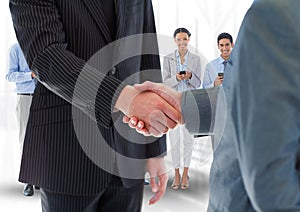 Composite image of Handshake in front of business people in office