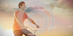 Composite image of handsome man on a bike ride on a sunny day