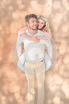 Composite image of handsome man giving piggy back to his girlfriend