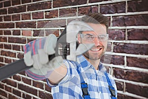 Composite image of handyman wearing protective glasses while holding wrench