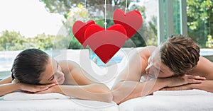 Composite image of hanging red heart and couple lying at spa