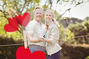 Composite image of hanging red hearts and couple embracing each other
