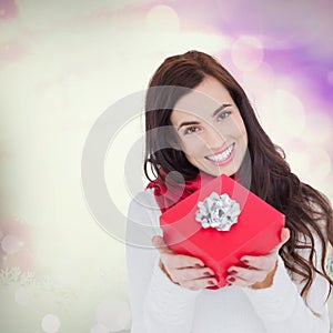 Composite image of happy brunette showing red gift with a bow