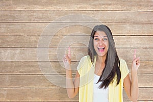 Composite image of happy casual woman pointing up