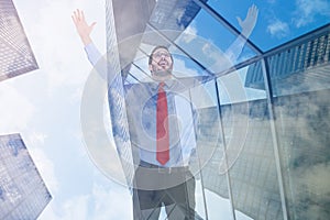 Composite image of happy cheering businessman raising his arms