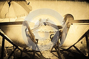 Composite image of happy couple clinking their glasses while relaxing on their deck chairs