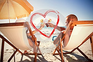 Composite image of happy couple clinking their glasses while relaxing on their deck chairs