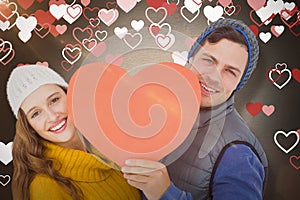 Composite image of happy couple holding heart shape paper