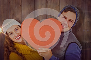 Composite image of happy couple holding heart shape paper