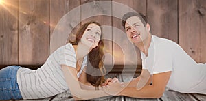 Composite image of happy couple lying on floor and looking up