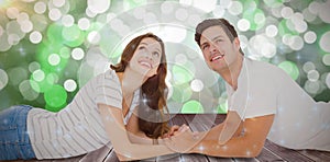 Composite image of happy couple lying on floor and looking up