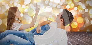 Composite image of happy couple lying on floor and pointing up