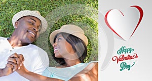 Composite image of happy couple lying in garden together on the grass