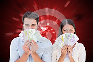 Composite image of happy couple showing their money