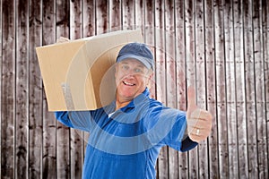 Composite image of happy delivery man holding cardboard box