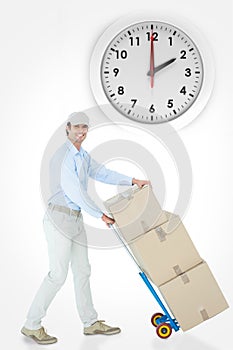 Composite image of happy delivery man pushing trolley of cardboard boxes