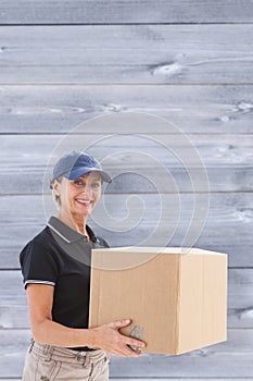 Composite image of happy delivery woman holding cardboard box