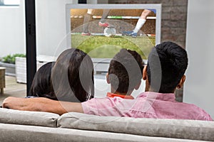 Composite image of happy family watching tv on the sofa